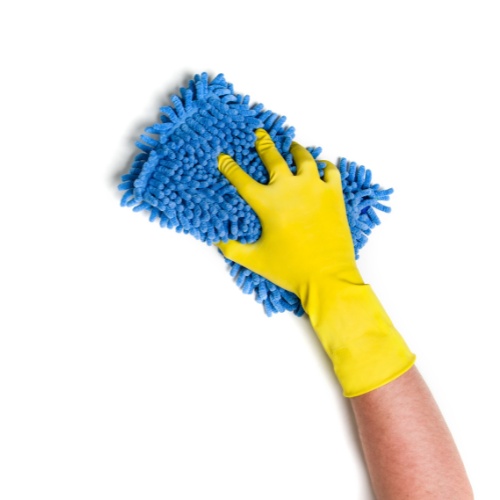 Hand wearing yellow glove holding a blue cleaning cloth