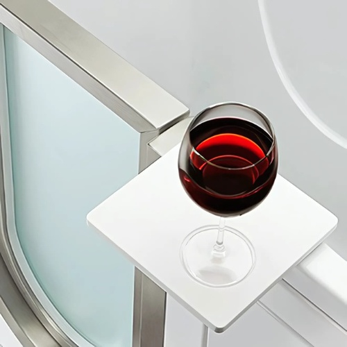 Wine glass placed on a built-in bath tray beside a tub door